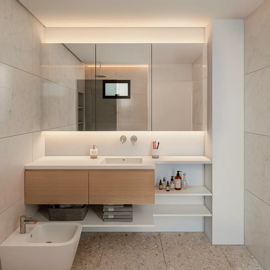 Render de baño con vanitory suspendido, iluminación indirecta y revestimiento beige